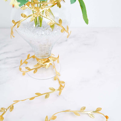 Gold leaf ribbon decoratively wrapped around a glass vase with flowers.