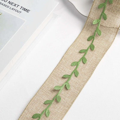 Green leaf ribbon on a neutral fabric background.