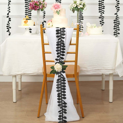 Elegant white chair cover with black leaf accents and rose decoration.