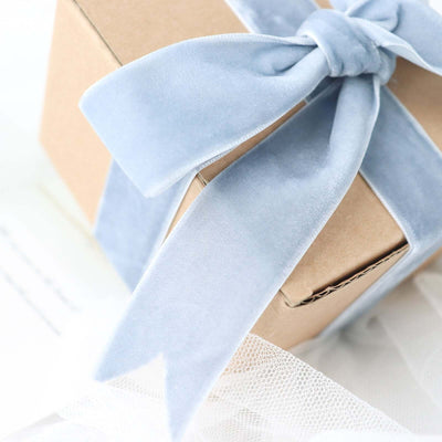 Blue velvet ribbon tied on a gift box with a soft, elegant texture.
