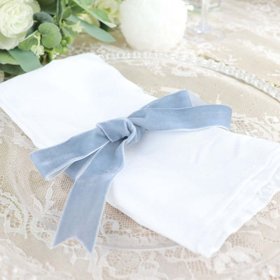 Elegant white napkin tied with a soft blue ribbon on a decorative table setting.
