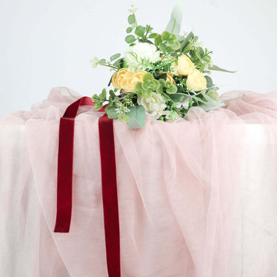 Floral arrangement with yellow roses and greenery on soft pink fabric