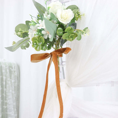 Floral bouquet with greenery and ribbon on a sheer backdrop.