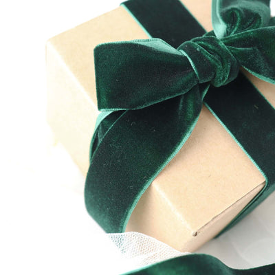 Green velvet ribbon tied around a kraft gift box.