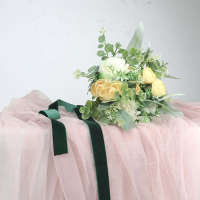 Floral bouquet with white and yellow flowers on pink fabric backdrop.
