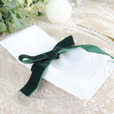 Elegant white napkin with green velvet ribbon on a decorative plate.