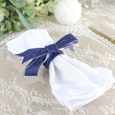 White napkin tied with navy ribbon on elegant table setting.