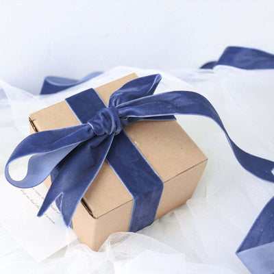 Gift box wrapped in navy ribbon on a soft white background.