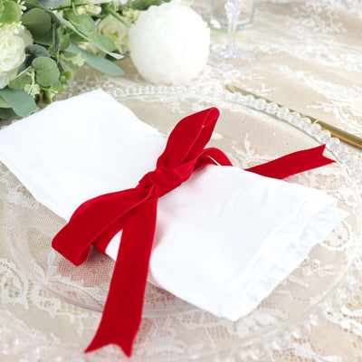 White napkin elegantly tied with a red ribbon on a decorative plate.