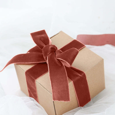 Gift box with a velvet ribbon on soft fabric background.