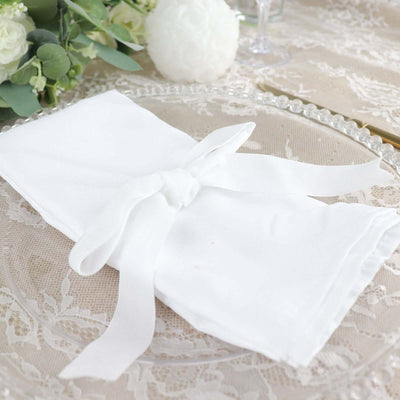 White linen napkin elegantly tied with a ribbon on a decorative plate.