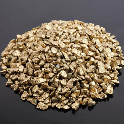Gold-colored gravel stones in a pile on a dark surface.