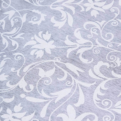 Floral patterned fabric with intricate white designs on a light gray background.