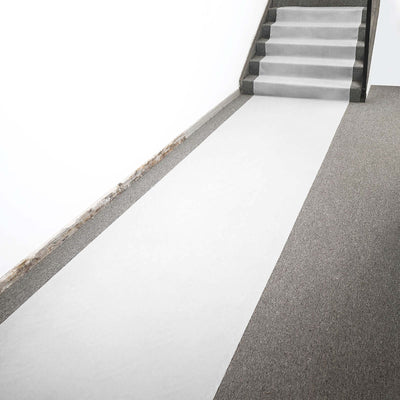 White runner carpet leading up a staircase on a gray floor