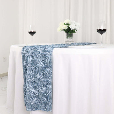 Blue rose-patterned table runner on a white table with wine glasses and flowers.