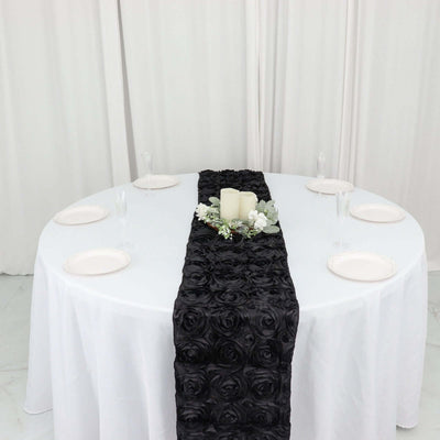 Black rose table runner on a white table setting with candles and floral decor.
