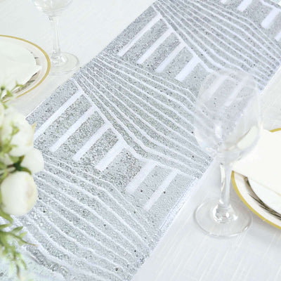 Silver patterned table runner on elegant dining table setting.