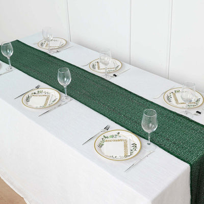 Elegant green table runner with decorative plates and glasses on a white table.
