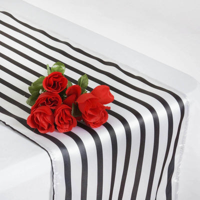Black and white striped table runner with red roses on top.