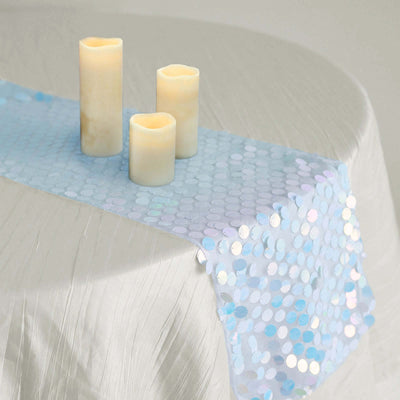 Table runner with iridescent sequins and three candles on a textured tablecloth.