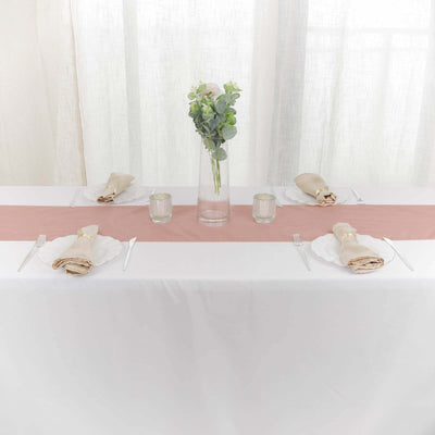 Elegant table setting with a pink runner, candles, and greenery vase.