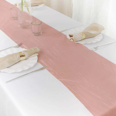 Pink table runner on a white table set for dining with elegant napkins and glassware.