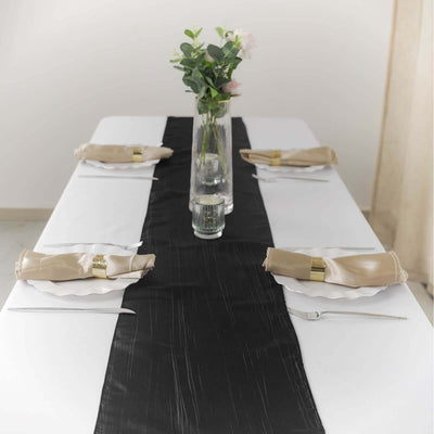 Elegant black table runner on a white table setting with napkins and floral centerpiece.