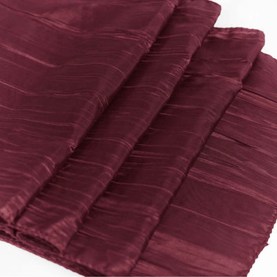 Burgundy textured fabric draped elegantly on a white surface.