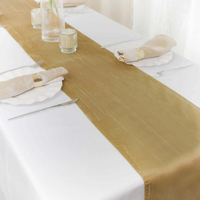 Elegant gold table runner on a white table setting with plates and cutlery.
