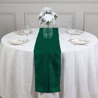 Green table runner on a white table with plates and floral centerpiece.