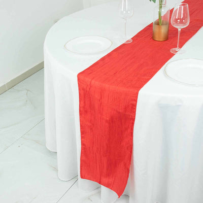 Red table runner on a round white table setting with wine glasses.