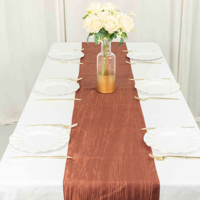 Table set with white plates and a brown runner, adorned with flowers in a vase.