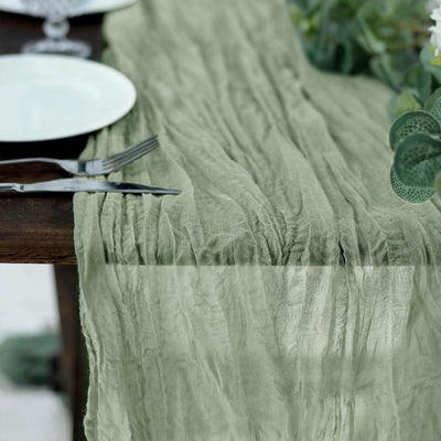 Wrinkled sage green table runner on a rustic wooden table setting.