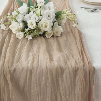 Elegant beige table runner with white floral arrangement on top.