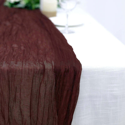 Burgundy crinkled table runner draped elegantly over a white tablecloth.