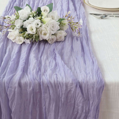 Purple crinkled table runner with white floral arrangement on a dining table.