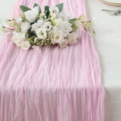 Pink table runner with white floral arrangement on a textured tablecloth.