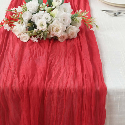 Red table runner with white floral arrangement on a textured table setting.