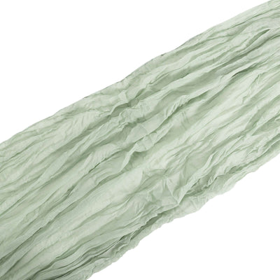 Light green crinkled fabric draped elegantly in studio isolation