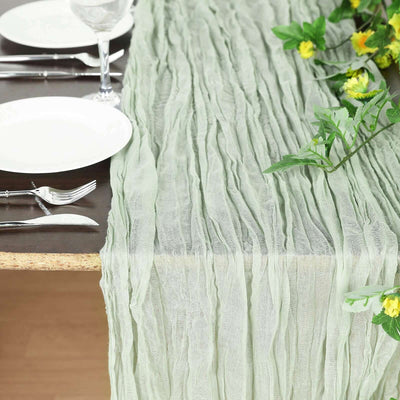 Green crinkled table runner on a dining table with plates and utensils.