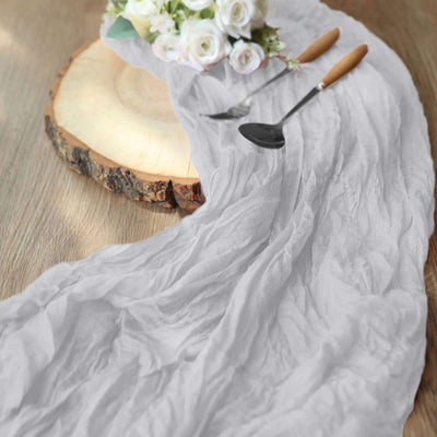 Gray textured table runner with serving utensils and floral arrangement.