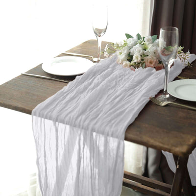 White textured table runner draped on a rustic wooden table with elegant dinnerware.