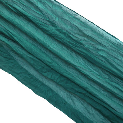 Crinkled teal fabric draped in waves on a white background.