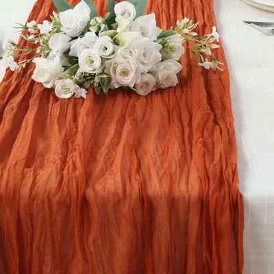 Rustic orange table runner with white floral arrangement on a dining table.