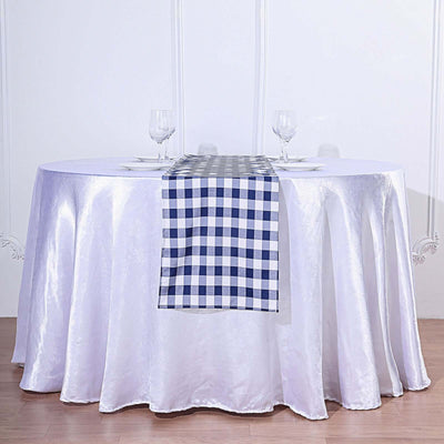 White table with a checkered table runner and two wine glasses.