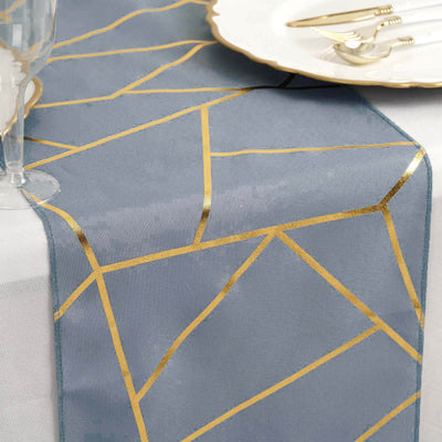 Gray table runner with gold geometric design on a dining table setting.
