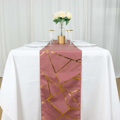 Rose gold table runner with geometric gold design on a white table.