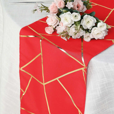 Red table runner with gold geometric design, styled with faux flowers.