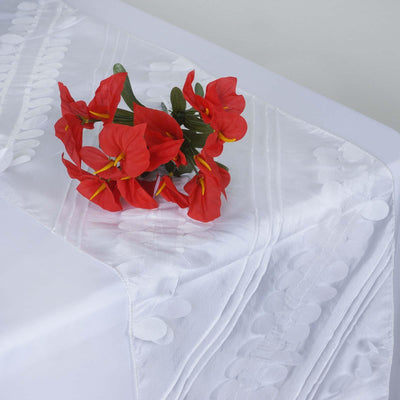 Red flowers on a white tablecloth with decorative patterns.