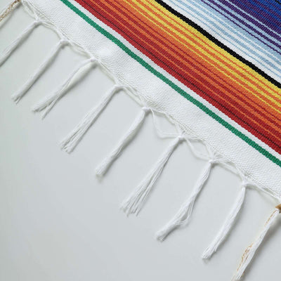 Colorful woven blanket edge with fringe details.